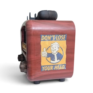 May include: A faux wood grain radio featuring a rectangular sticker with a cartoon character giving a thumbs up inside a blue circle. The sticker includes the text DON'T LOSE YOUR HEAD in blue capital letters on a yellow background.