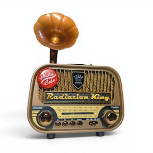 Può includere: Una radio in stile vintage nei toni dell'oro e del marrone, con un altoparlante a tromba decorativo. La radio presenta il testo "Radiation King" e "Nuka Cola". Include manopole del volume e della sintonizzazione.