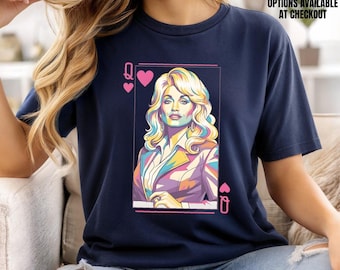 May include: A navy blue short-sleeve t-shirt featuring a graphic print of a blonde woman styled as a playing card queen. The design includes pink heart symbols and a rectangular border. The shirt is made of Bella Canvas fabric in navy.