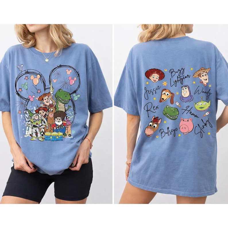 May include: A light blue t-shirt featuring a graphic of Toy Story characters, including Woody, Buzz Lightyear, and Rex, with a Mickey Mouse outline. The back of the shirt displays character names. A comfortable, casual style.