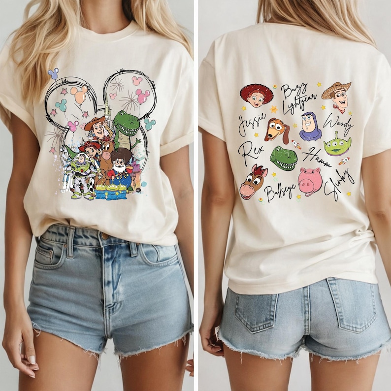 May include: Cream-colored t-shirt featuring a Disney-themed graphic on the front and back. The front design includes a Mickey Mouse head outline with Toy Story characters. The back displays individual character portraits and names.