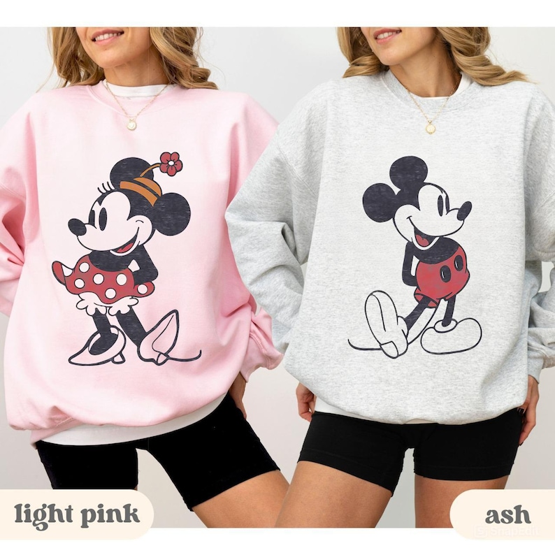 May include: Two sweatshirts, one light pink and one ash, each featuring a classic cartoon character. The light pink sweatshirt has a Minnie Mouse graphic, while the ash sweatshirt displays Mickey Mouse. The text "light pink" and "ash" are at the bottom.