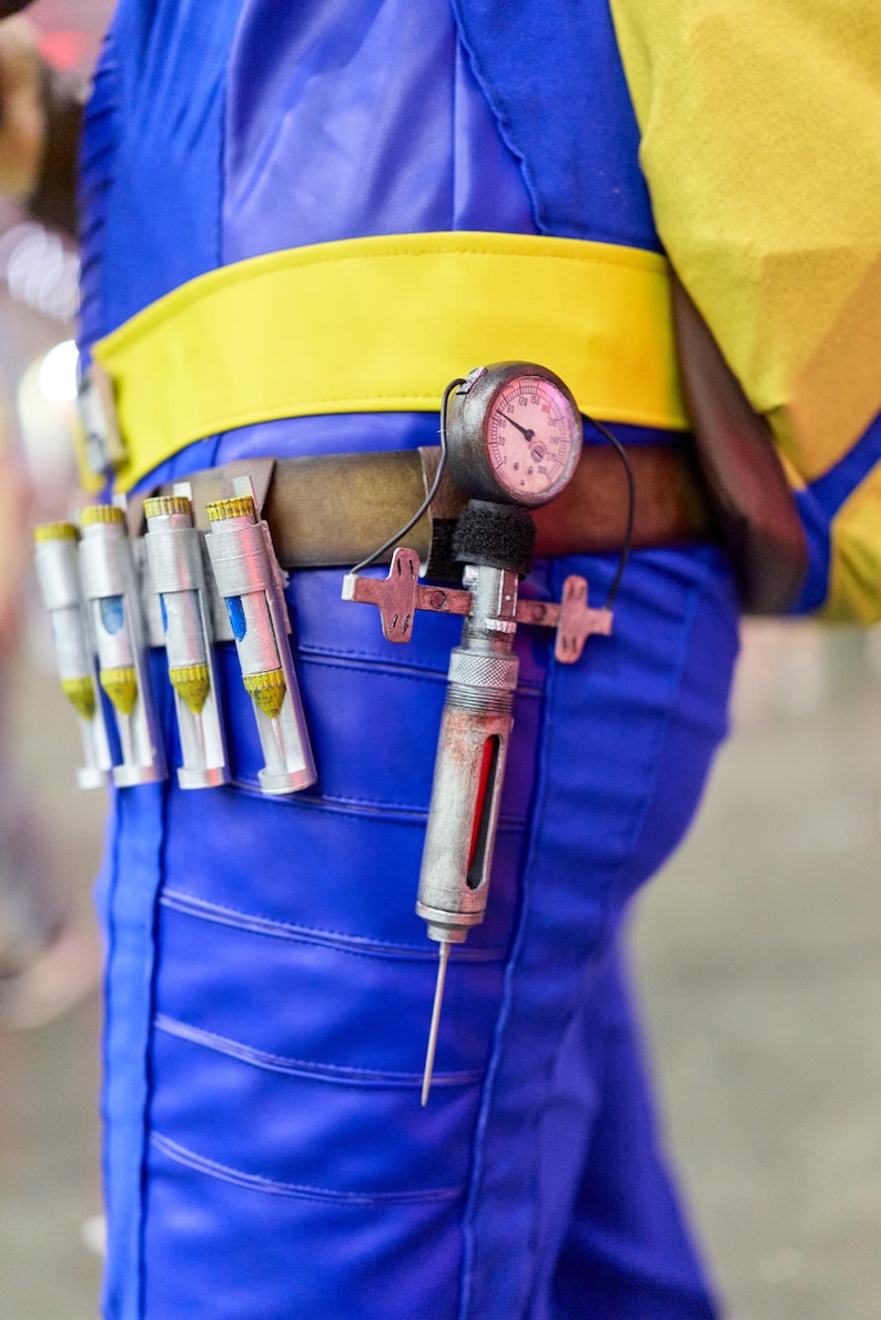 May include: A blue and yellow costume with a utility belt featuring a pressure gauge and several silver vials. The belt is brown with a yellow stripe. The costume is blue with yellow accents.