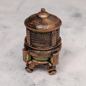 Könnte beinhalten: Ein bronzefarbenes, zylindrisches Dekorationsobjekt mit gewölbtem Deckel und drei kleinen Beinen. Das Objekt hat eine strukturierte Oberfläche und horizontale Linien in der Mitte. Grüne Akzente sind an der Basis sichtbar.