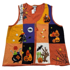May include: A sleeveless knit vest featuring a patchwork design in orange, purple, black, and white. The vest displays embroidered Halloween motifs including pumpkins, a witch, bats, spiderwebs, candy corn, and a cauldron with a pumpkin-shaped zipper pull.
