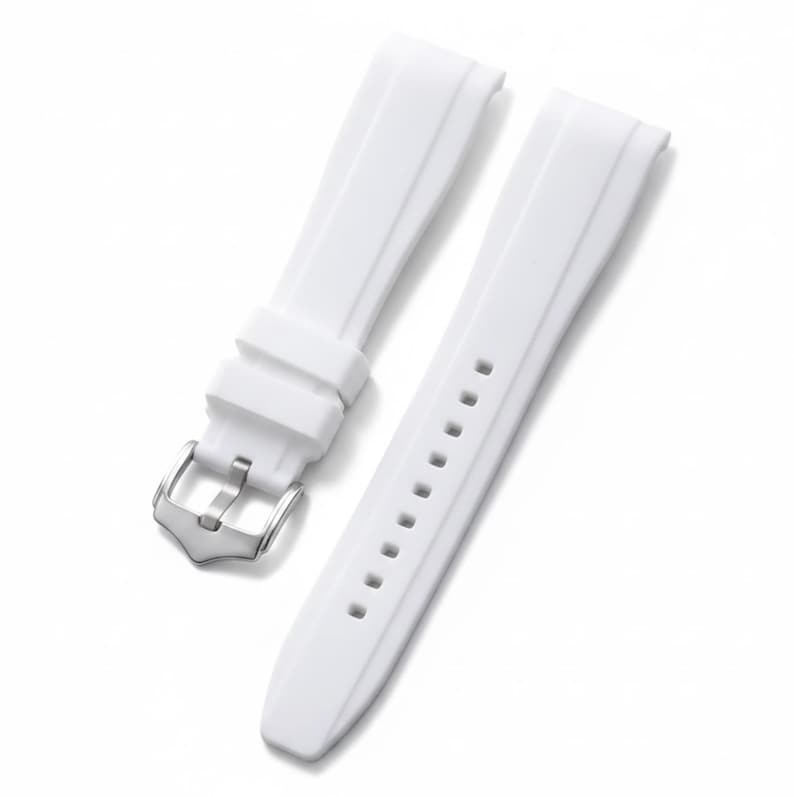 K&ouml;nnte beinhalten: Ein wei&szlig;es Silikon-Uhrenarmband mit glatter, flexibler Textur und einer mittig verlaufenden, erhabenen Leiste auf beiden Teilen. Es verf&uuml;gt &uuml;ber eine silberfarbene Metall-Dornschlie&szlig;e und zwei passende wei&szlig;e Silikon-Schlaufen zur Befestigung.
