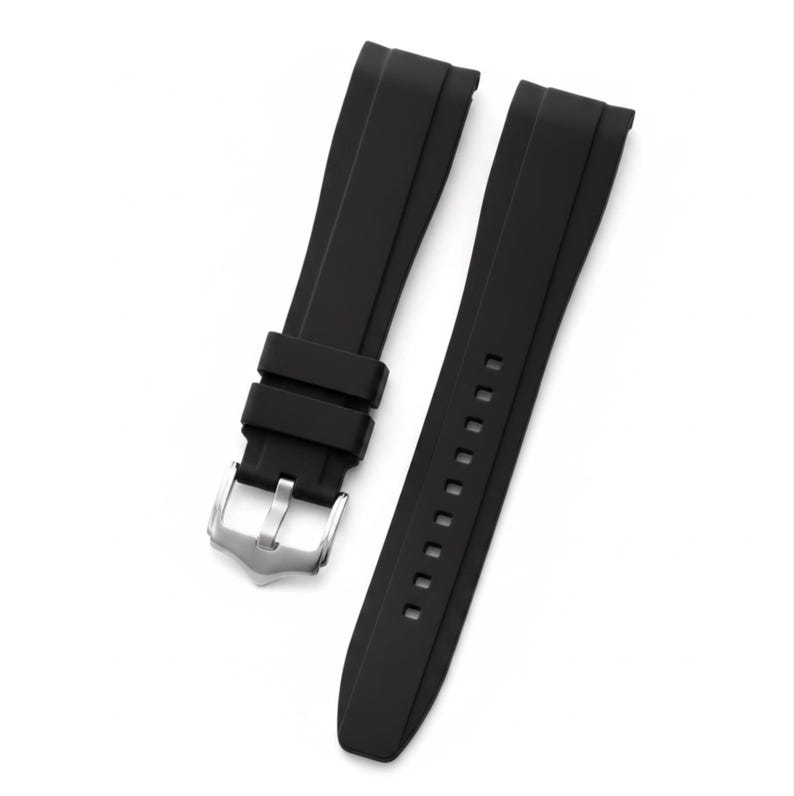 K&ouml;nnte beinhalten: Ein schwarzes Uhrenarmband aus Kautschuk, bestehend aus zwei separaten Teilen. Ein Teil verf&uuml;gt &uuml;ber eine silberfarbene Dornschlie&szlig;e aus Metall und zwei verschiebbare Schlaufen, w&auml;hrend das andere Teil eine Reihe rechteckiger L&ouml;cher aufweist.