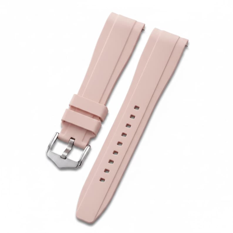 K&ouml;nnte beinhalten: Ein hellrosa Uhrenarmband aus Gummi mit glatter, matter Oberfl&auml;che und einer silberfarbenen Metallschnalle. Das Armband besteht aus zwei separaten Teilen, wobei eine Seite eine Reihe von Einstelll&ouml;chern und die andere eine Metall-Dornschlie&szlig;e aufweist.