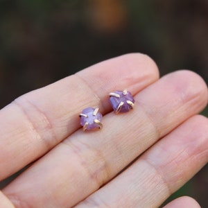 Puede incluir: Un par de pendientes con pequeñas piedras preciosas púrpuras en bruto engastadas en oro.