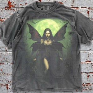 Step into the mystical night with this Vintage Gothic Fairy T-Shirt 🌙🖤. Printed on premium Comfort Colors fabric, this oversized tee blends witchy gothic vibes with a bold moonlit fairy illustration. Perfect for Y2K, grunge, and dark aesthetic lovers, this washed retro graphic shirt makes a unique unisex gift for him or her.
