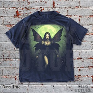 May include: Navy blue t-shirt featuring a gothic fairy design with a full moon backdrop, bats, and spiders. The fairy has large, detailed wings and is wearing a dark dress. The text "Navy True" is at the bottom left.
