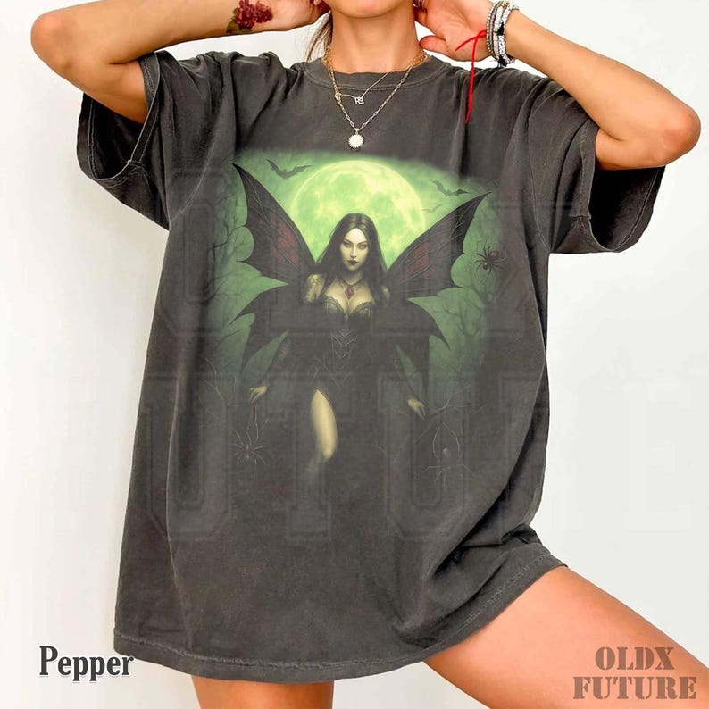 May include: Dark gray t-shirt featuring a gothic fantasy illustration of a woman with bat wings, set against a green moonlit backdrop. The design includes bats and spiders. The word "Pepper" is printed on the bottom left.
