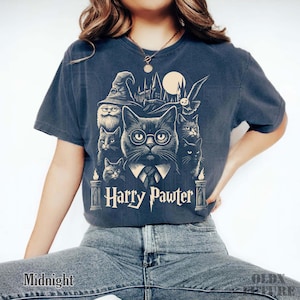 May include: Midnight blue t-shirt featuring a graphic of cats in a wizard theme. The design includes a cat wearing glasses and a tie, with the text "Harry Pawter" below. The shirt has a vintage, distressed look.