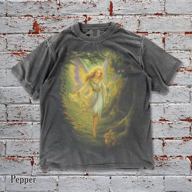 ✨ Step into a magical forest with this vintage oversized Comfort Colors tee 🌙🧚. Featuring a glowing fairy with butterfly friends and a rabbit, this shirt blends fantasy, gothic charm, and retro style. 100% cotton, washed vintage look, and a baggy oversized fit make it perfect for Y2K lovers, nature fans, and whimsical fashion seekers 🎁🖤.