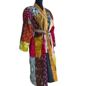 May include: A patchwork robe in a variety of colors, including red, yellow, blue, and purple. The robe has a shawl collar and a matching belt. The robe is made of different fabric patterns.