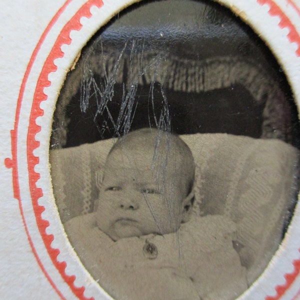 antique tintype photo - 1800s, baby sitting in a chair wearing a gold locket, paper frame