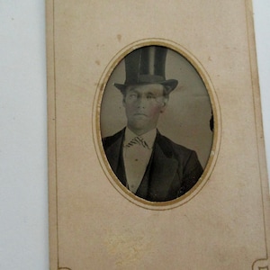 antique tintype photo - 1800s, man with top hat, tinted cheeks, in paper frame