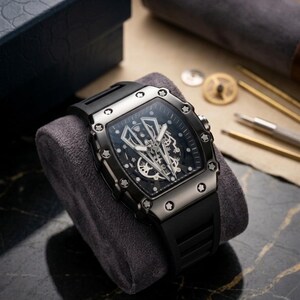 May include: A black wristwatch with a rectangular face and a black rubber strap. The watch has a detailed, open-face design, showcasing the inner workings. The watch is displayed on a grey velvet cushion.