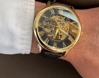 Reloj mecánico esqueleto: esfera dorada y negra, correa de cuero.