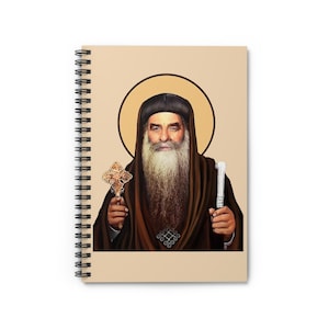 Könnte beinhalten: Spiralgebundenes Notizbuch mit einem Porträt einer religiösen Figur. Die Figur hat einen langen weißen Bart, trägt eine dunkle Robe und hält ein Kreuz und einen Stab. Der Hintergrund ist hellbeige mit einem goldenen Heiligenschein.