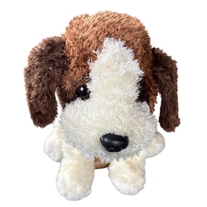 May include: A plush toy dog with brown and white fur. The dog has floppy ears, a black nose, and black eyes. The toy is designed to resemble a beagle puppy.