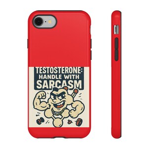 Puede incluir: Funda de teléfono roja con una ilustración de dibujos animados de un personaje musculoso sosteniendo una barra y un cigarrillo. El texto en la funda dice "TESTOSTERONE: HANDLE WITH SARCASM".