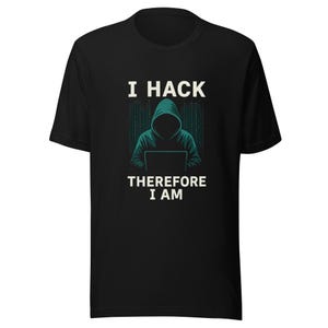 May include: Black t-shirt with the text "I HACK THEREFORE I AM" in white. The graphic features a hooded figure in teal, sitting in front of a laptop with a matrix-style background. The shirt is a short-sleeved crew neck.