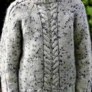 May include: A cream-coloured, hand-knitted jumper with a cable knit design down the centre. The jumper has a speckled pattern of grey and blue throughout. The jumper has a crew neck and long sleeves. A cosy and warm garment for cooler weather.