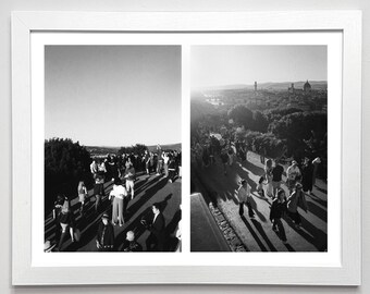 May include: Black and white framed print featuring two landscape views. The left panel shows a crowd of people on a pathway. The right panel shows a cityscape with a bright sun in the background. The frame is white.