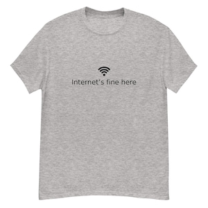 Könnte beinhalten: Graues T-Shirt mit schwarzem WLAN-Symbol und dem Text "Internet's fine here". Das Shirt hat einen Rundhalsausschnitt und kurze Ärmel. Die Grafik befindet sich mittig auf der Vorderseite.