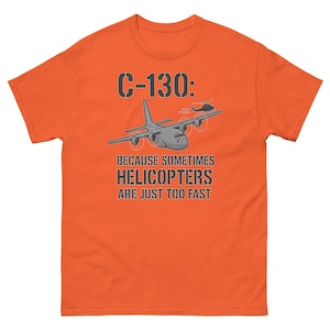 Może przedstawiać: Pomarańczowa koszulka z grafiką samolotu transportowego C-130 i helikoptera. Tekst brzmi "C-130: BECAUSE SOMETIMES HELICOPTERS ARE JUST TOO FAST". Projekt jest w odcieniach szarości i czerni.