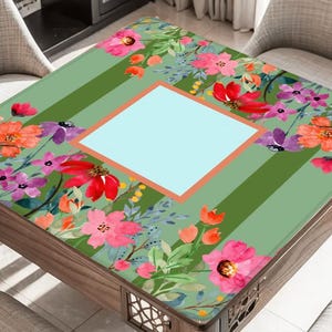 Puede incluir: Mesa cuadrada de madera con dise&ntilde;o floral. La tapa tiene un fondo verde claro con rayas verticales y un cuadrado azul claro central. El patr&oacute;n floral incluye flores rosas, rojas y moradas. La mesa mide aproximadamente 76 cm cuadrados.