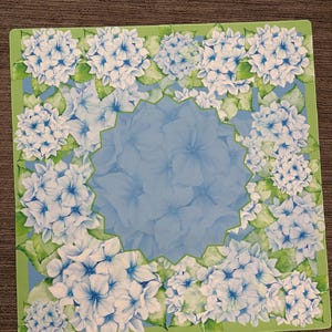 May include: Square decorative tray featuring a floral hydrangea design. The tray has a light blue center with a scalloped edge, surrounded by white and blue hydrangea blooms and green leaves on a light green border.