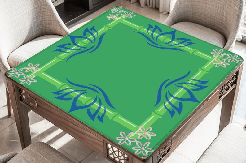 May include: A square wooden table with a green top featuring a bamboo and floral design. The table's surface has blue lotus flower motifs in each corner. The table is surrounded by chairs.