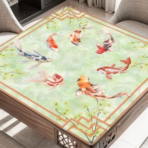 May include: A square wooden table with a decorative top featuring a watercolour design of koi carp in orange, red, and white against a green background. The table has a brown border and decorative cutouts.