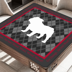 May include: A square table cover featuring a white bulldog silhouette on a gray and black argyle pattern. The border is black with a red trim and the text "Go Dawgs...Sir eat Woof, Woof, Woof!"