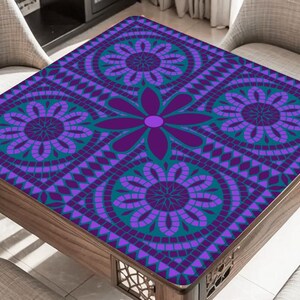 May include: A square wooden table with a decorative floral pattern in shades of purple and teal. The table's surface features a mosaic-like design with large flower motifs and geometric shapes. The table is surrounded by chairs with light-colored upholstery.