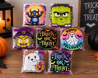 May include: Seven clear plastic treat bags filled with sweets, each featuring a unique Halloween-themed card topper. Designs include a blue monster, Frankenstein, a witch, a ghost, and text reading Trick or Treat and Happy Halloween.