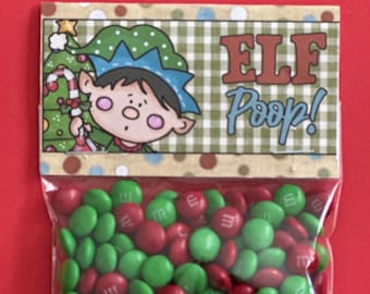 Puede incluir: Una bolsa de plástico transparente llena de caramelos rojos y verdes, con una etiqueta decorativa. La etiqueta presenta una ilustración de un elfo y las palabras "ELF Poop!" sobre un fondo a cuadros verde y blanco, sobre un fondo rojo.