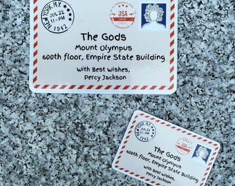 Könnte beinhalten: Zwei rechteckige Karten mit rot-weißem Rand, Text und Briefmarken. Die Karten lauten "The Gods, Mount Olympus, 600th floor, Empire State Building" und "With Best Wishes, Percy Jackson."