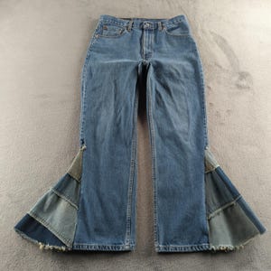 May include: Light blue denim jeans with flared patchwork panels at the hem. The jeans feature a classic five-pocket design and a button and zip closure. The patchwork panels are made of various shades of blue denim, creating a unique and eye-catching look.