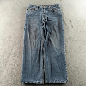 May include: Light blue denim jeans with a classic five-pocket design. The jeans have a straight leg cut and a button and zip closure. The denim has a faded appearance, with subtle wear marks.