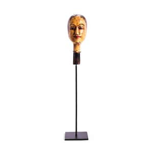 Puede incluir: Una escultura de cabeza de madera tallada con rasgos faciales pintados, incluyendo cabello oscuro, cejas arqueadas y labios rojos. La cabeza está montada sobre una varilla de metal negro delgada unida a una base cuadrada de metal negro.