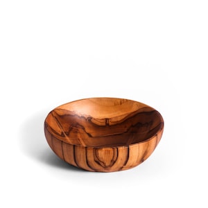 May include: A small, wooden bowl with a natural, warm brown color. The bowl has a rounded shape and a smooth, polished finish. The wood grain is visible, adding to its rustic charm. This bowl is perfect for serving snacks or as a decorative piece.