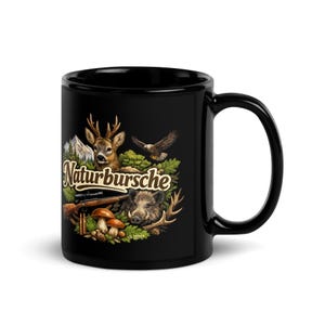 Op de afbeelding: Zwarte keramische mok met een jachtthema. Het ontwerp bevat een hert, een adelaar, een wild zwijn, een geweer en paddenstoelen, met de tekst "Naturbursche". De mok heeft een glanzende afwerking en een gebogen handvat.