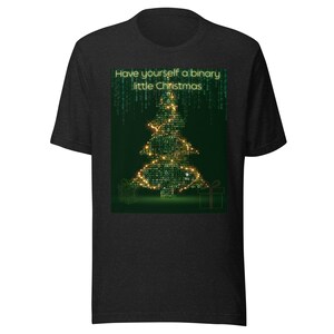 Może przedstawiać: Ciemnoszara koszulka z motywem choinki wykonanym z kodu binarnego i napisem "Have yourself a binary little Christmas". Drzewko jest oświetlone złotymi światełkami, a u podstawy znajdują się dwa pudełka z prezentami.