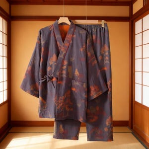 May include: A two-piece set of Japanese-style loungewear. The set includes a kimono-style jacket with a tie closure and matching pants. The fabric is a dark gray with a pattern of orange trees and foliage. The jacket has a red trim.