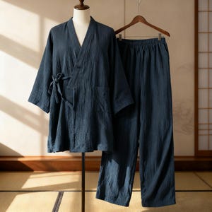 Op de afbeelding: Een marineblauwe katoenen kimono-achtige robe met bijpassende broek. De robe heeft een V-hals, een striksluiting en een zak. De broek heeft een elastische tailleband. De set wordt gepresenteerd op een mannequin en een hanger.