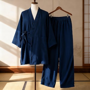 May include: A navy blue pajama set displayed on a mannequin and a hanger. The set includes a wrap-style top with a tie closure and a pair of matching pants. The fabric appears to be lightweight and breathable, suitable for sleepwear or loungewear.