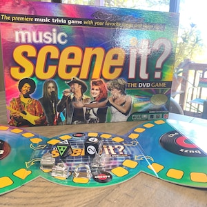 May include: A board game titled "Music Scene It?" with a colorful box featuring images of musicians. The game board is open, displaying dice and game pieces. The text "The premiere music trivia game" is visible.